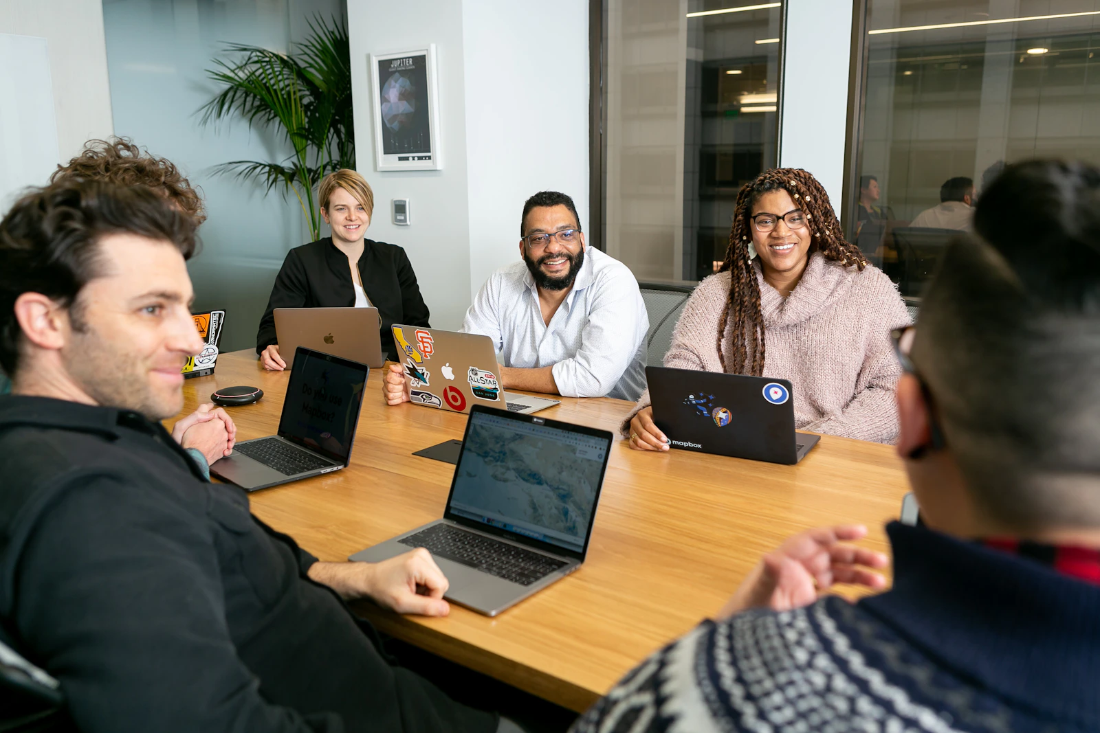 A small business team reviewing a vendor pitch presentation around laptops